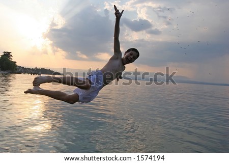 Boy joyfully jumping in the lake at sunset