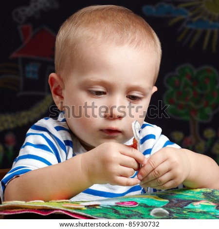 Toddler boy playing with a colorful felt book
