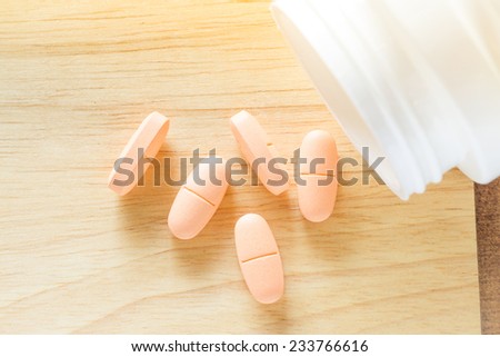 vitamin tablets from plastic bottle on wood table