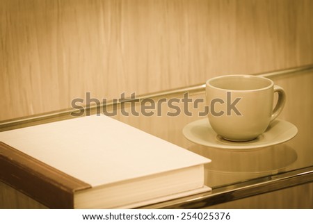cup of coffee and book on table in vintage tone