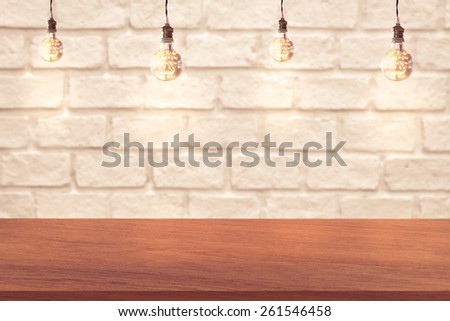 edge of wood table and white brick wall background with light bulbs