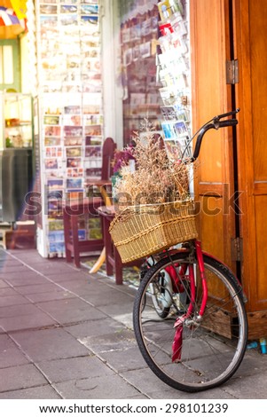 vintage bicycle with flower basket in front of postcard shop