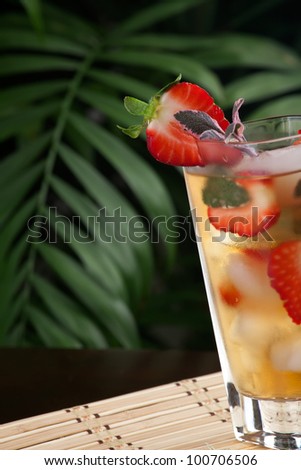 Closeup of glass of strawberry and sage iced tea on a table in a restaurant on a tropical beach.