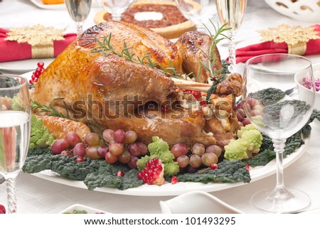 Holiday-decorated table, Christmas tree, champagne, and roasted turkey.