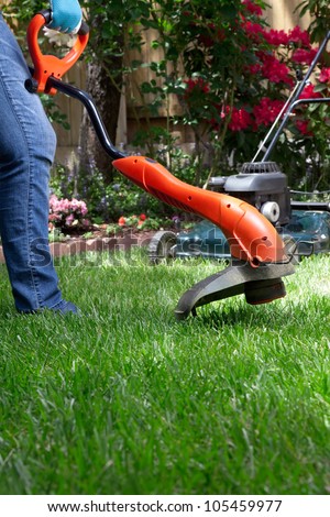 Woman is trimming her lawn with electric edge trimmer.