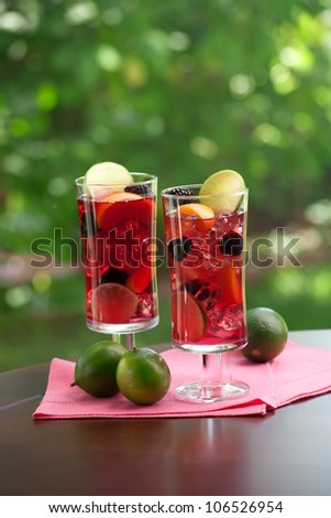 Closeup of two glass of Red Sangria - apricot, lime and blackberry - on outside table.