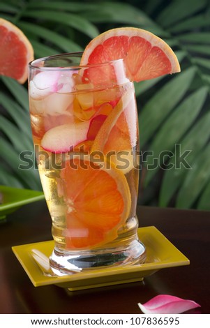 Closeup of glass of grapefruit and rose iced tea on a table in a restaurant on a tropical beach.