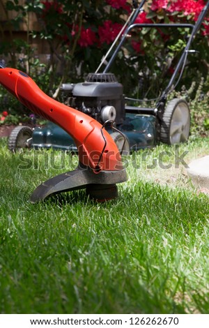Woman is trimming her lawn with electric edge trimmer.
