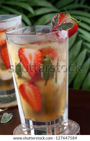 Two glasses of glass of strawberry and sage iced tea on a table in a restaurant on a tropical beach.