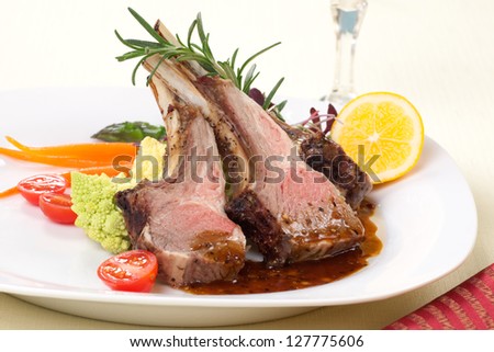 Rosemary roasted lamb chops (ribs) garnished with asparagus, glazed carrots,, grape tomatoes, and micro greeens.