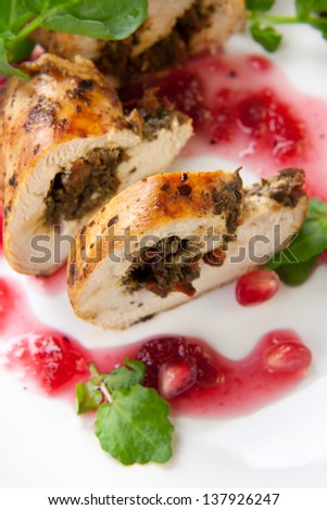 Dried cranberry and pesto stuffed chicken breast roulade with potato, watercress, and pomegranate sauce
