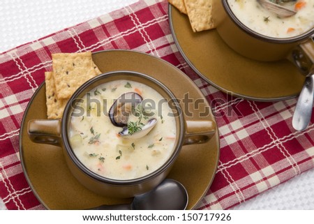 Bowls of hot delicious clam chowder garnished with fresh thyme, and multy grain crackers