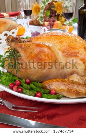 Garnished roasted turkey on fall festival decorated table with horn of plenty and red wine