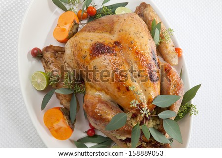 Garnished roasted turkey with tropical fruits over white background for Thanksgiving