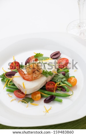 Poached halibut with spicy shrimp, green beans, cherry tomatoes, black olives, and citrus sauce.