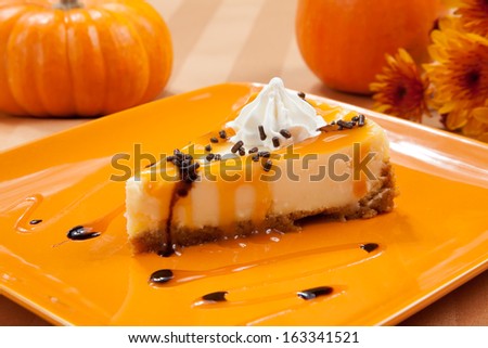 Caramel cheesecake with whipped cream and chocolate sprinkles with pumpkins and flowers in fall theme.