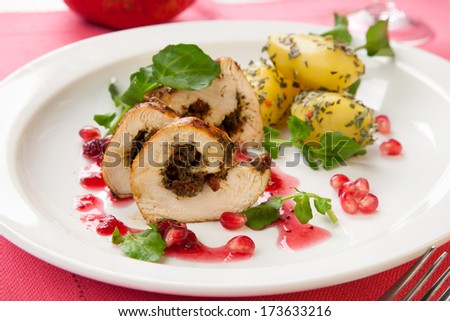 Dried cranberry and pesto stuffed chicken breast roulade with potato, watercress, and pomegranate sauce