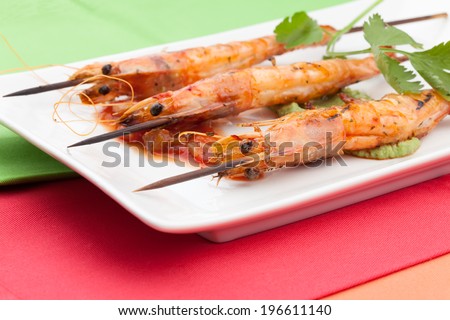 Delicious large spicy grilled whole shrimps -scampi- with salsa and guacamole sauces and fresh cilantro.