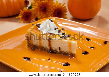 Sprinkle covered cheesecake with caramel and chocolate syrup with pumpkins and flowers in fall theme.