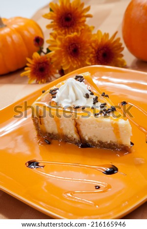 Sprinkle covered cheesecake with caramel and chocolate syrup with pumpkins and flowers in fall theme.