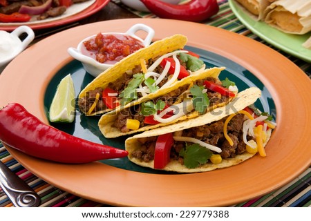 Assorted Mexican dishes, with whole grain corn beef tacos as the main subject.