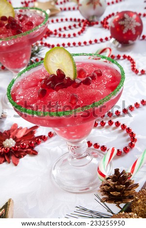 Two frozen pomegranate margaritas cocktails on Christmas decorated holiday table with Christmas ornaments. Holiday cocktails series.