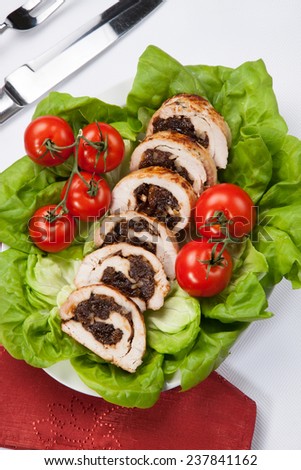 Delicious turkey breast roulade cut in slices stuffed with prunes and almond. Garnished with butter lettuce and tomatoes on vines.