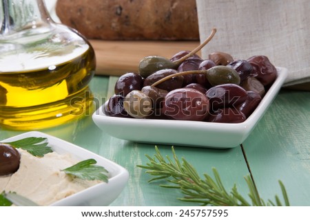 Greek style black olives, hummus, olive oil, and bread on a wooden table