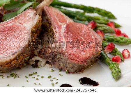 Herb crusted lamb chops (ribs) garnished with asparagus, carrots, and pomegranates. Mini pumpkins and fresh fruits