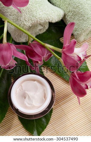 Dark pink blooming Cymbidium orchid flowers and moisturizing face cream for everyday.