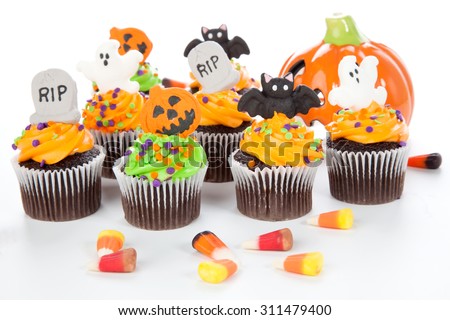 Halloween cupcake with RIP, ghost, bat, and  jack-o'-lanÃ?Â·tern decorations surrounded by Halloween cupcakes, corn candies, and decoration.