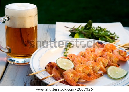 Grilled shrimps on wood sticks served with lime and mug of pale ale