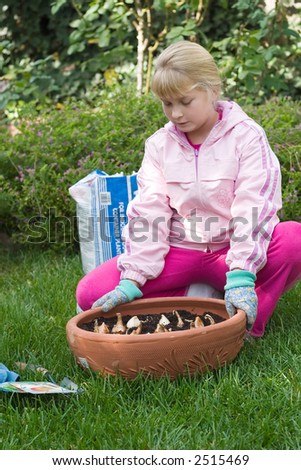 Girl outside in the garden planting spring bulbs into container on fall