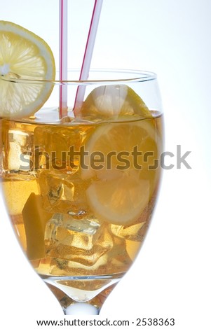 Single tall glass of iced tea full of ice cubes, slices of lemon and two straws over white background