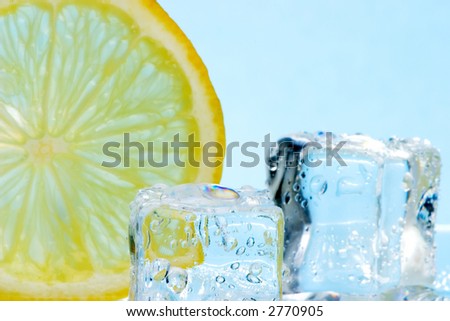 Two ice cubes melted in water and slice of lemon on reflection surface ready to be added to a cocktail