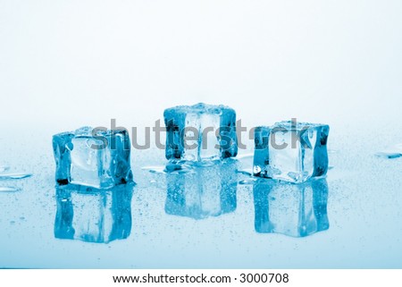 Three azure colored ice cubes melted in water on reflection surface ready to be added to a cocktail