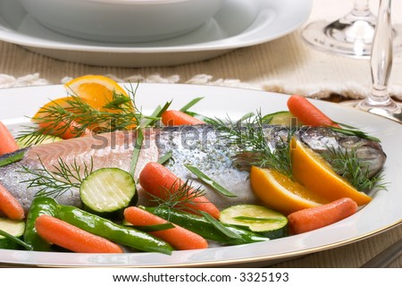 Organic whole trout cooked with vegetables, green salad and glass of wine served for dinner