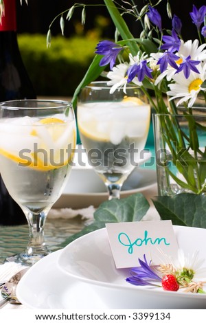 Formal poolside dinner table setting with name cards in plates ready for party to start