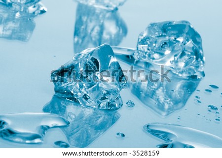Azure colored ice cubes melted in water on reflection surface ready to be added to a cocktail