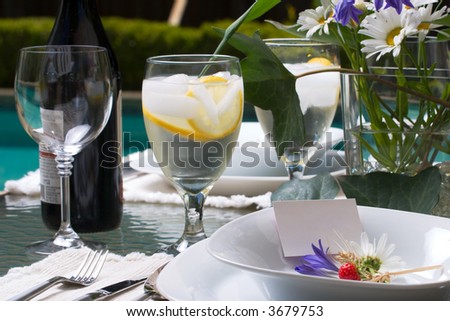 Formal poolside dinner table setting with name cards in plates ready for party to start