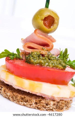 Closeup of delicious Pesto cheese and ham canape-sandwich made from Pesto, cheese, ham, tomato and olive
