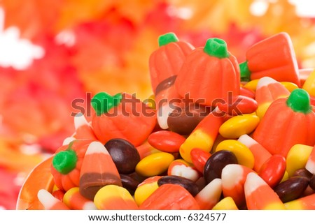 Closeup of pumpkin filled with delicious Halloween candy over fall leaves background