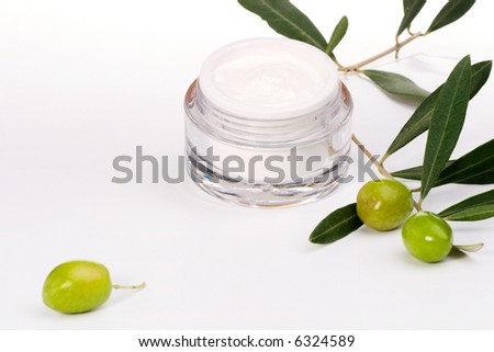 Closeup of jar of moisturizing face cream and twig with green olives.