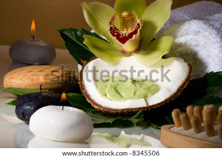 Avocado coconut scrub in coconut shell, orchid flower (Cymbidium sp.) and candles. Suited for relaxing and health commercials