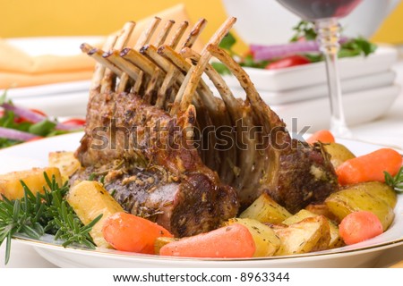 Rack of Lamb (ribs) with Rosemary garlic dressing, garnished with baby carrots, potatoes and rosemary sprigs. Dinner settings.