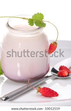 Closeup of open jar of organic yogurt and delicious wild strawberries