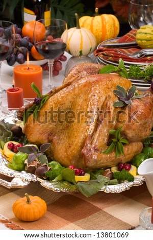 Garnished roasted turkey on holiday decorated table with pumpkins and glasses of red wine