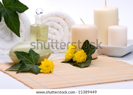 Spa set - Chrysanthemums flowers, aroma candles, oils, organic soap on bamboo mat and towels with ivy leaves over white background best suited for relaxing and health commercials