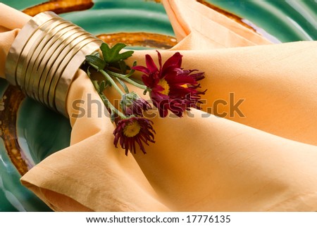 Closeup of napkin and mums for fall festive theme dinner table arrangement