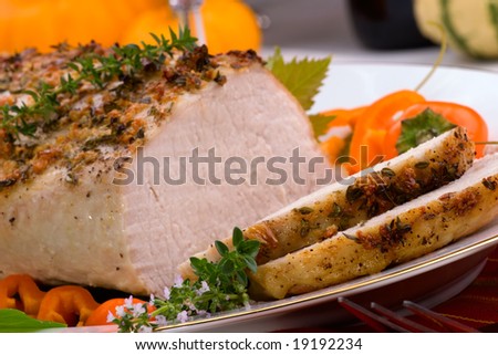Delicious sliced garlic thyme roast pork loin is ready for dinner in middle of fall arrangement table.